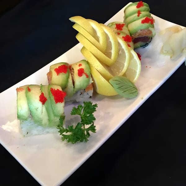 Wild Wok's sushi rolls with avocado, red roe, lemon slices, and parsley on a white plate.